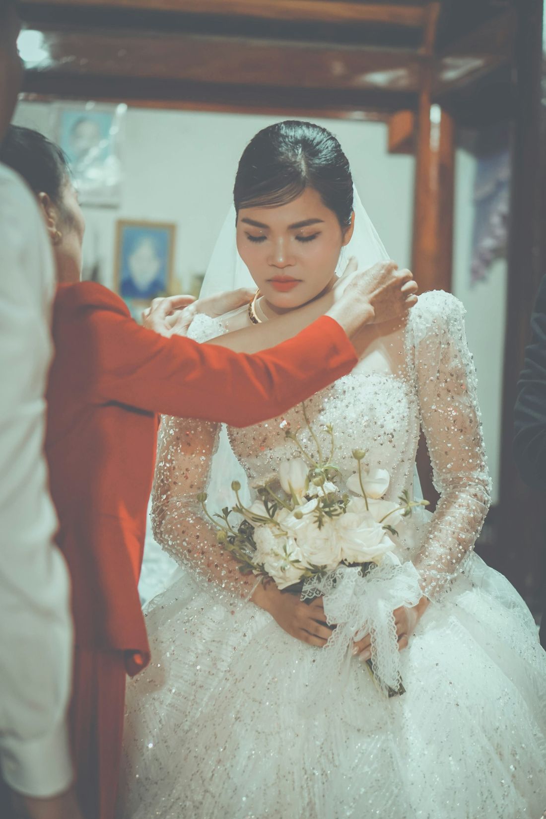 Veil being placed on a bride in a beaded gown