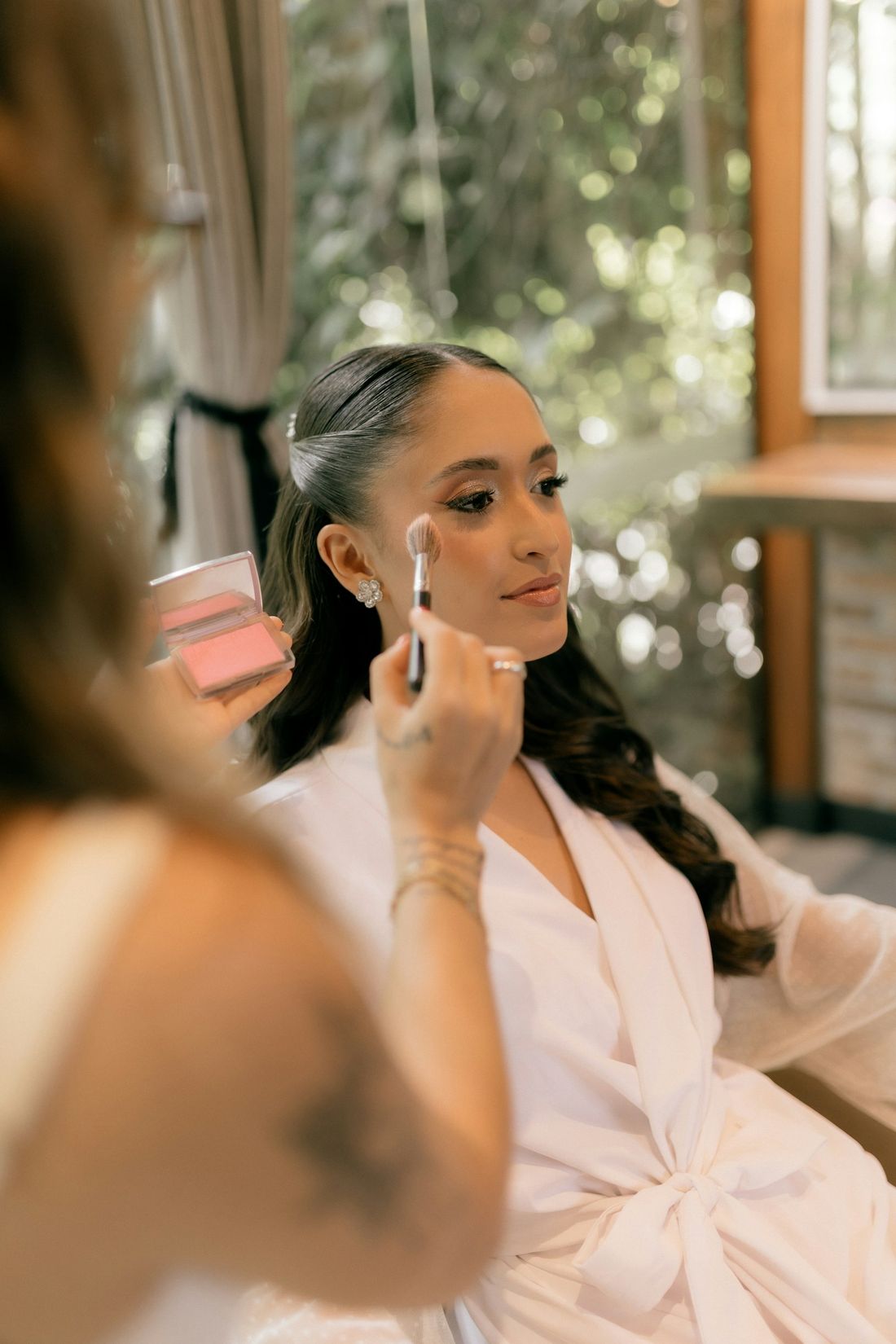 Celine finishing a bride's makeup by the window